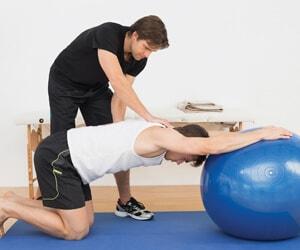 Physical therapist assisting a patient with a stability ball