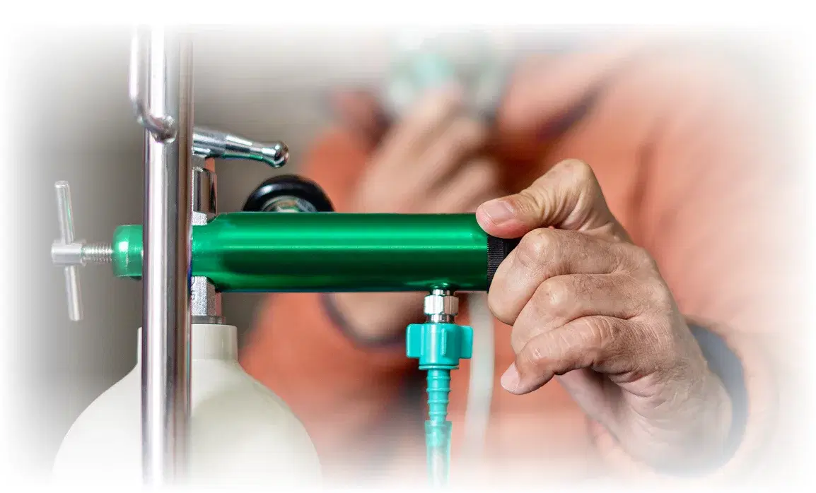A hand adjusting the regulator on a home oxygen cylinder.